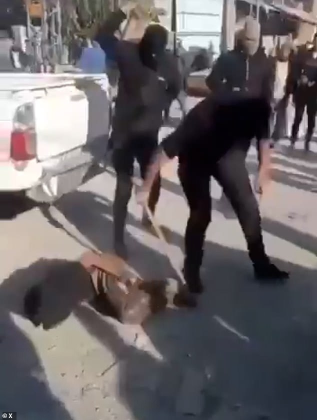 An alleged Palestinian civilian is seen writing on the floor in pain as he is beaten by two masked man while bound with his hands behind his back