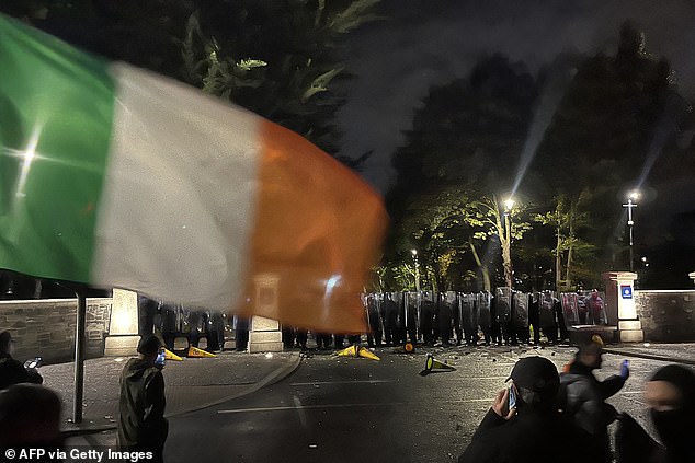 Protesters face a line of police at a demonstration outside a hotel housing asylum seekers in Dublin