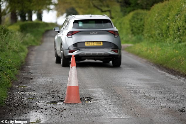 A traffic cone warns drivers of a pothole on the road on April 25, 2024 near Northwich, United Kingdom.