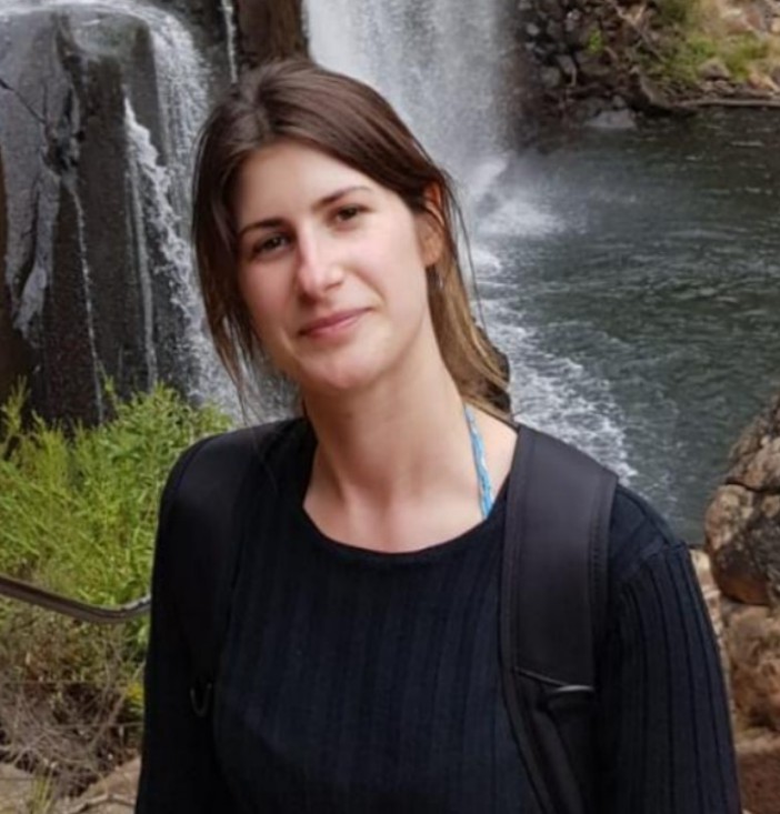 Young woman smiling with a waterfall in the background.