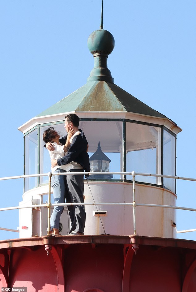 The actors put on an animated display, waving from the top of the landmark before moving in for a kiss