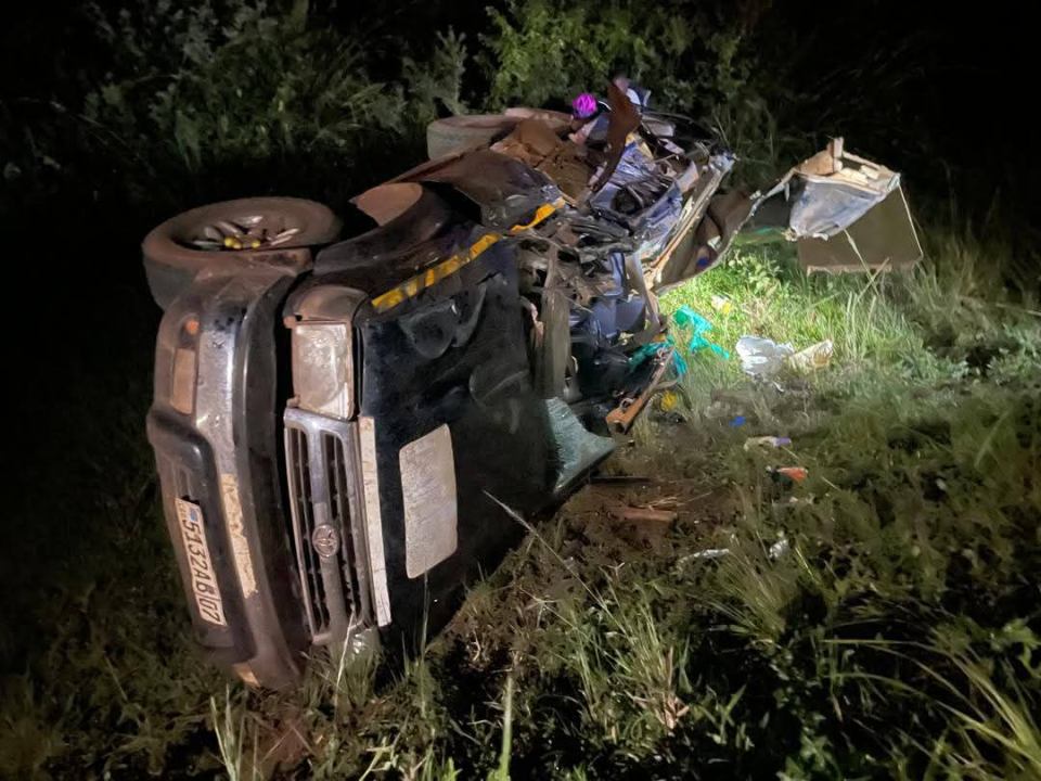 Overturned and crashed black vehicle at night.