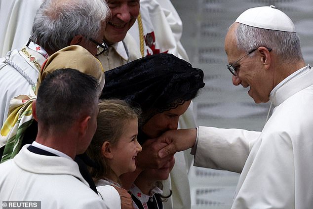 A woman kisses the hand of Pope Leo XIV during a meeting at the Vatican this morning