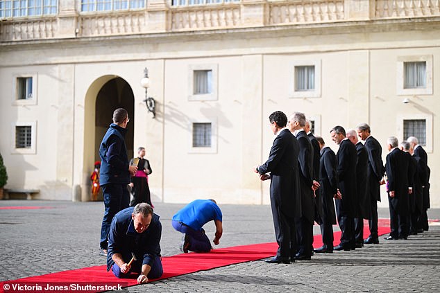 Workers set up a red carpet at Vatican City today ahead of the arrival of the King and Queen