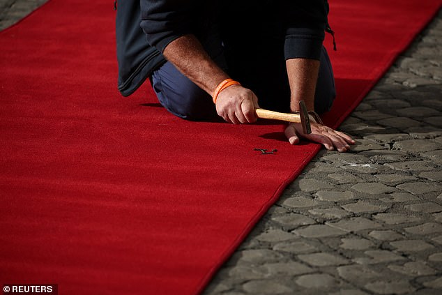 Workers set up a red carpet at Vatican City today ahead of the arrival of the King and Queen