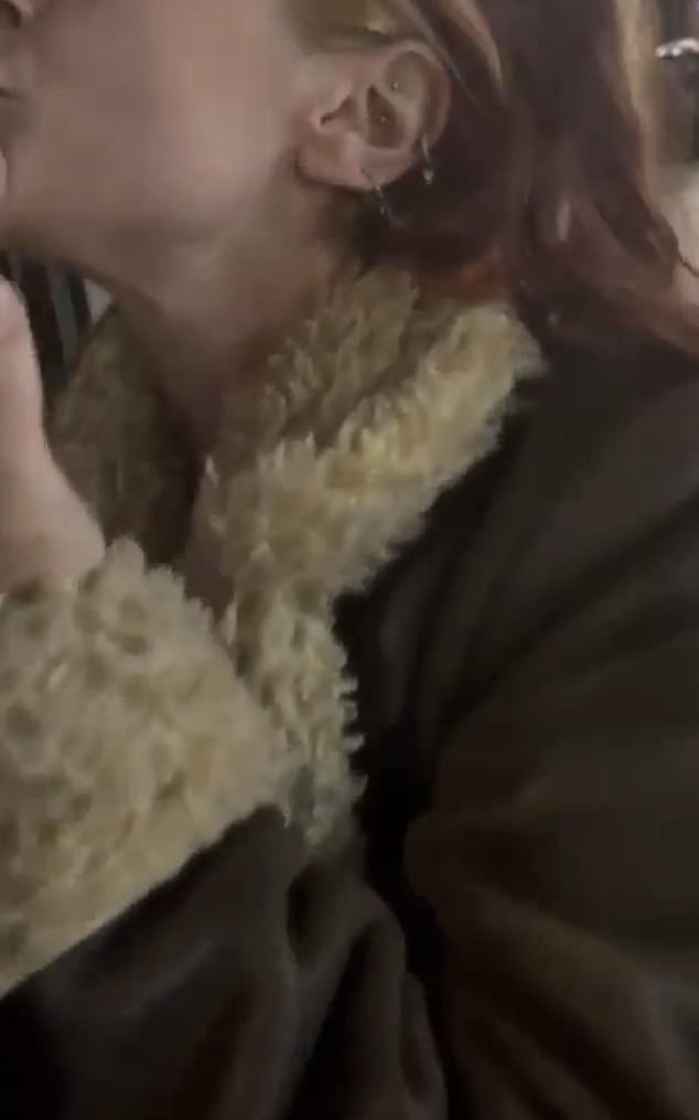 Shocking footage shows the young brunette woman with blonde highlights hawking her saliva at the graphic on an advertising display outside Hendon Central underground station