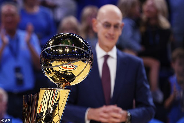 NBA commissioner Adam Silver stands behind the Larry O'Brien trophy during a ceremony before an NBA basketball game between the Houston Rockets and Oklahoma City Thunder, Tuesday, Oct. 21, 2025, in Oklahoma City. (AP Photo/Nate Billings)