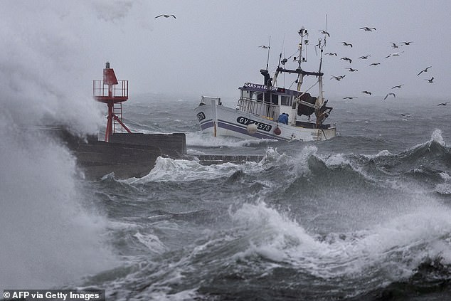 A fishing boat arrives at the port in Plobannalec-Lesconil, western France, October 22, 2025, as huge waves and strong winds hit the coast at the passage of the storm Benjamin