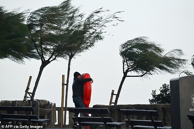 A man clings to a lifebuoy near the 'Grande Plage', in Biarritz, south-western France on October 23, 2025
