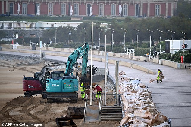 Mechanical shovels lay bags full of sand to protect the promenade of the 'Grande Plage', in Biarritz, south-western France on October 23, 2025