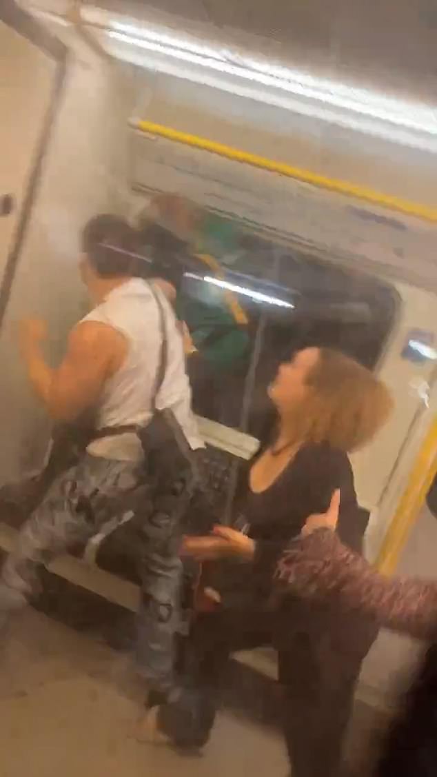 Footage filmed inside a Tube shows a man in a brightly coloured carnival costume scuffling with a group of other revellers