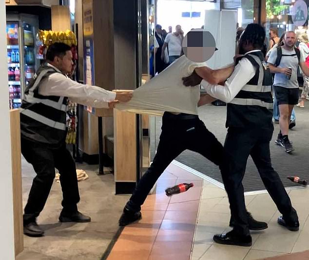 Fightback: Security guards eject a thief from a Greggs in Hammersmith, West London. Coke bottles went flying as the man resisted security guards as they tried to evict him from the premises
