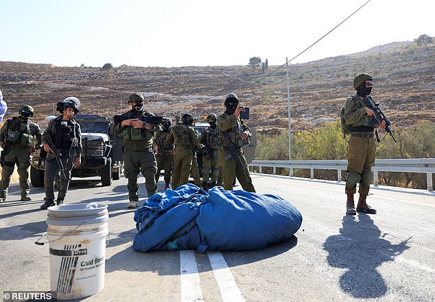 Members of the Israeli forces stand guard during the olive harvest, near Hebron, in the Israeli-occupied West Bank, October 23, 2025