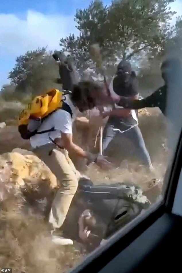 This Oct. 19, 2025, image taken from video shows what appear to be masked settlers beating activists and Palestinian farmers in Turmus Ayya, West Bank