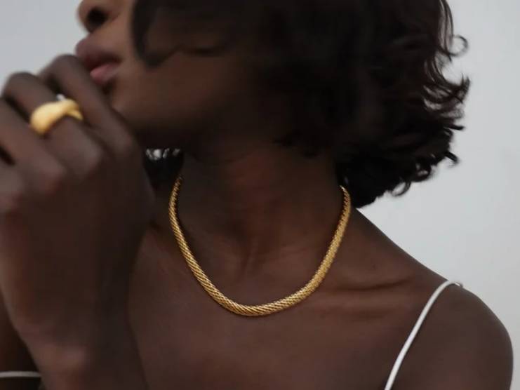 Person wearing gold necklace and ring.