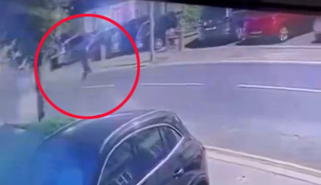 The footage shows a figure, dressed in dark clothing, crossing the seemingly empty Redbridge Lane East in Ilford, northeast London