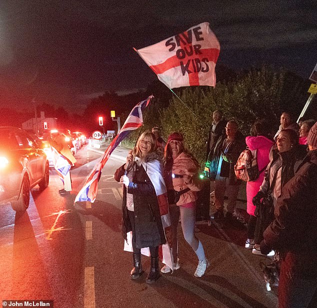 People (pictured) held Union flags and a St George's Cross which read 'Save our Kids' outside the hotel on Friday