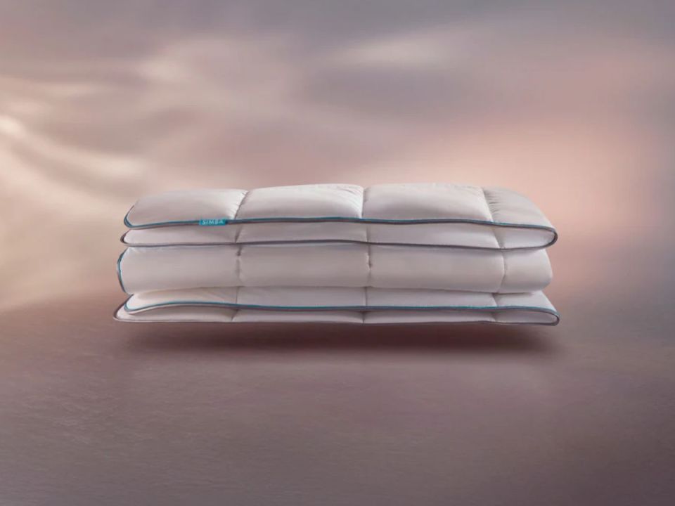 Three white folded comforters with blue piping.