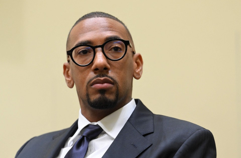 Jerome Boateng in a suit and glasses, looking forward.