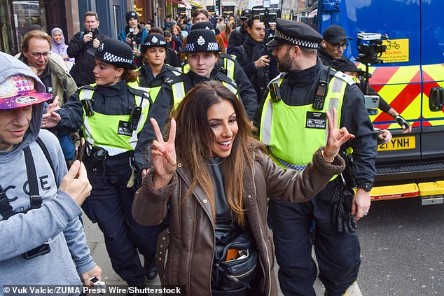 TV personality Narinder Kaur is led away by police officers after she confronted far right protesters