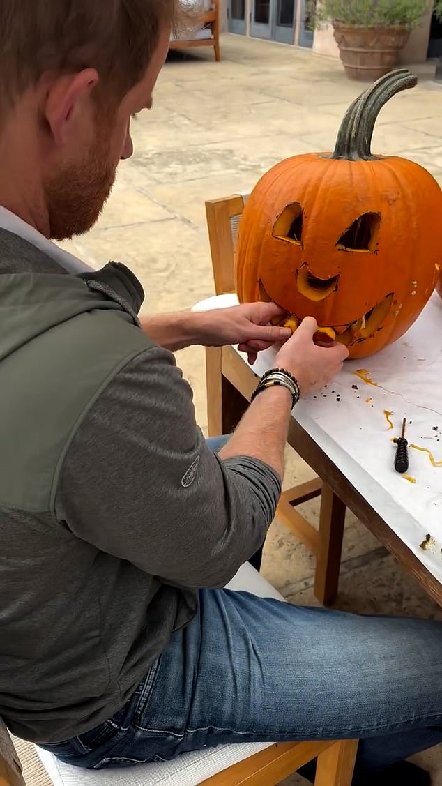 The children watch on in awe at their father, Prince Harry, carving a pumpkin just in time for the spooky season