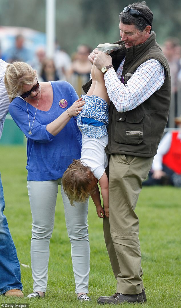 She seems to have a similarly loving relationship with Princess Anne's husband, Sir Timothy Laurence, who playfully dangled her upside down while smiling at the Badminton Horse Trials in 2016 (pictured, with Autumn Phillips, the ex-wife of Anne's older brother Peter Phillips)