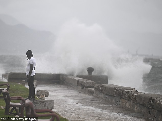 A man watches the waves crash into the walls at the Kingston Waterfront on October 27, 2025