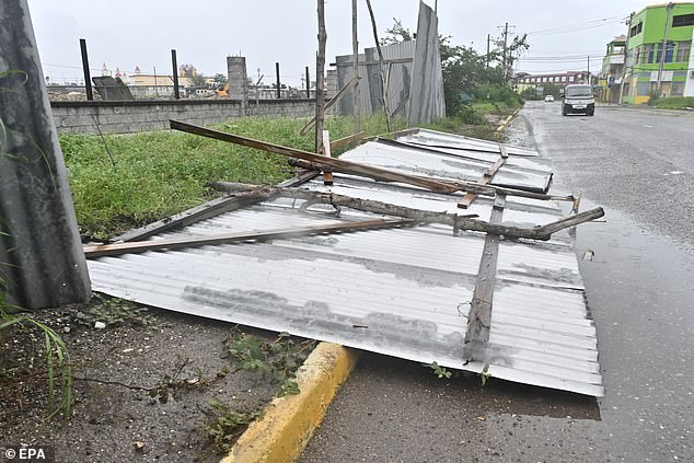 A fence lays on the road having been blown over by the powerful winds of Hurricane Melissa