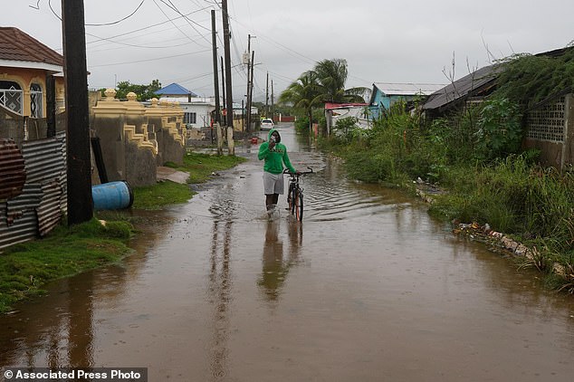 A man wades through a flooded street ahead of the forecasted arrival of Melissa in Old Harbour