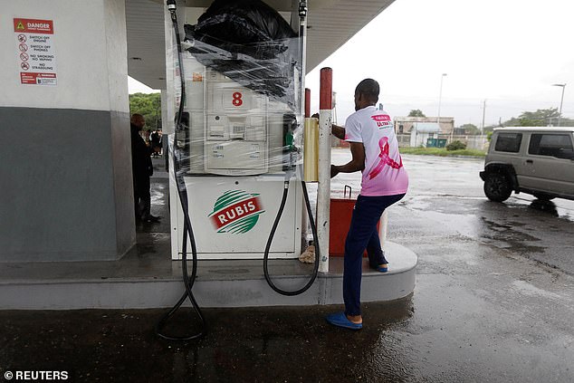 A man wraps a petrol pump as Hurricane Melissa approaches, Kingston, Jamaica, on Monday