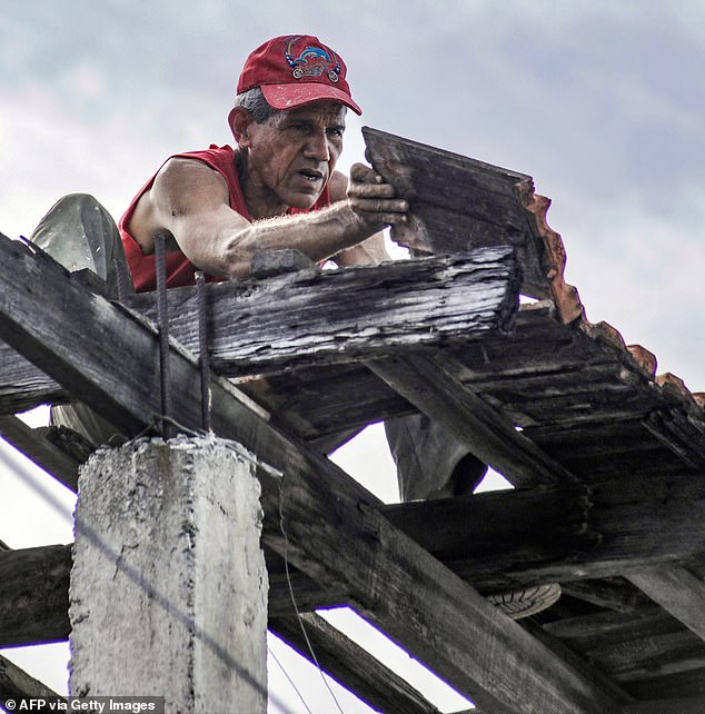 A man attempts to secure the roof of his home ahead of the arrival of Hurricane Melissa on Monday
