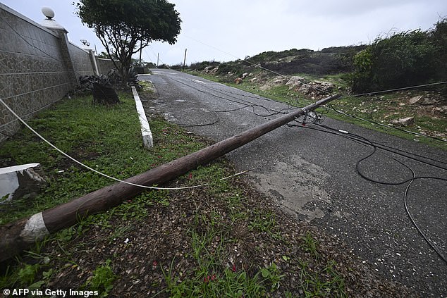 A fallen Jamaica Public Service Company light pole is seen on the Sugar Man's beach main road in Hellshire, St Catherine parish, near Portmore, as Jamaica starts to feel the effects of Hurricane Melisa on October 26, 2025