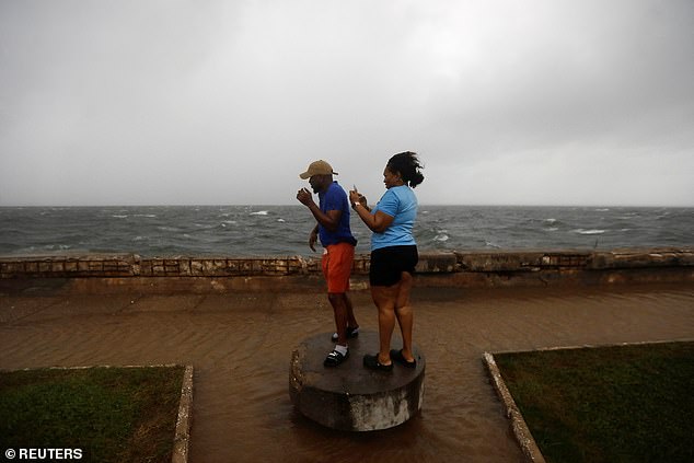 People stand along the Kingston waterfront as Hurricane Melissa approaches, in Kingston, Jamaica, on Monday