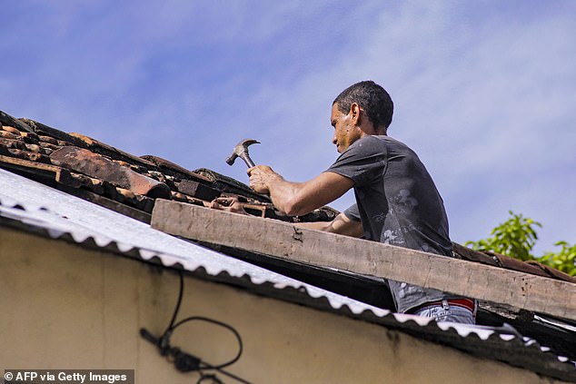 A man hammers the roof of his home ahead of the arrival of Hurricane Melissa on Monday