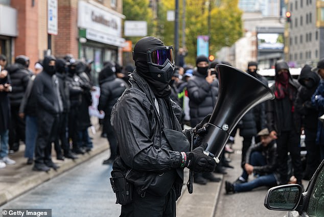 A masked man standing with a megaphone in Whitechapel