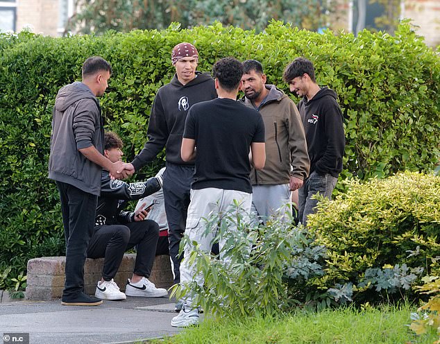 Asylum seekers loiter outside the Roundhouse Hotel, one of three migrant hotels in Bournemouth, in October