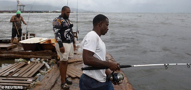 Michael Wright, John Tamasa and Socrates Reynolds fish ahead of Hurricane Melissa, in Portmore, Jamaica, October 26, 2025.  REUTERS/Octavio Jones