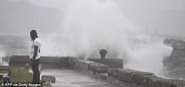 A man watches the waves crash into the walls at the Kingston Waterfront on October 27, 2025. Hurricane Melissa threatened Jamaica with potentially deadly rains after rapidly intensifying into a top-level Category 5 storm, as residents scrambled for shelter from what could be the island's most violent weather on record. Melissa has already been blamed for at least four deaths in Haiti and the Dominican Republic, and was set to unleash torrential rains on parts of Jamaica in a direct hit on the Caribbean island. (Photo by Ricardo Makyn / AFP) (Photo by RICARDO MAKYN/AFP via Getty Images)