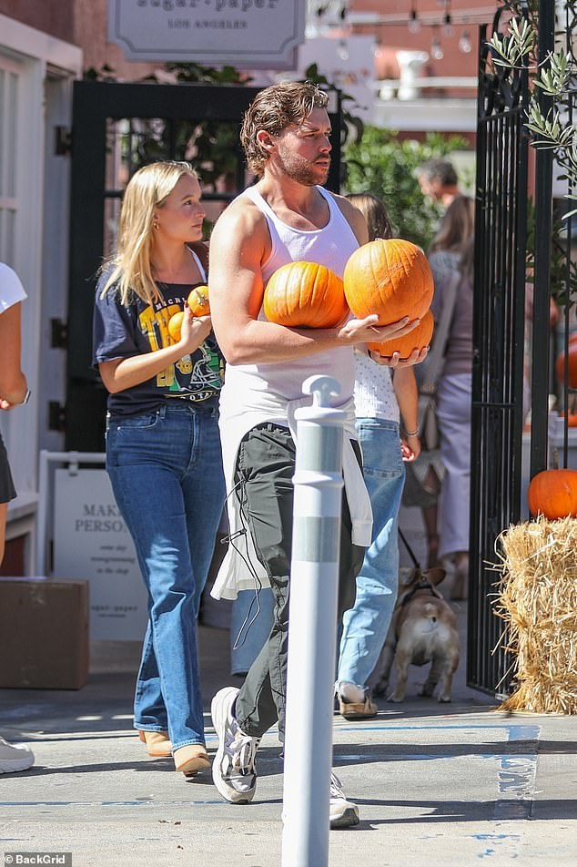 Christopher's mystery blonde companion sported a vintage Michigan University Wolverines T-shirt, along with blue jeans, and tan suede heeled booties