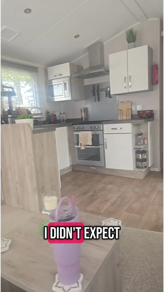 A modern kitchen in a caravan with a microwave, oven, and wood-look flooring.