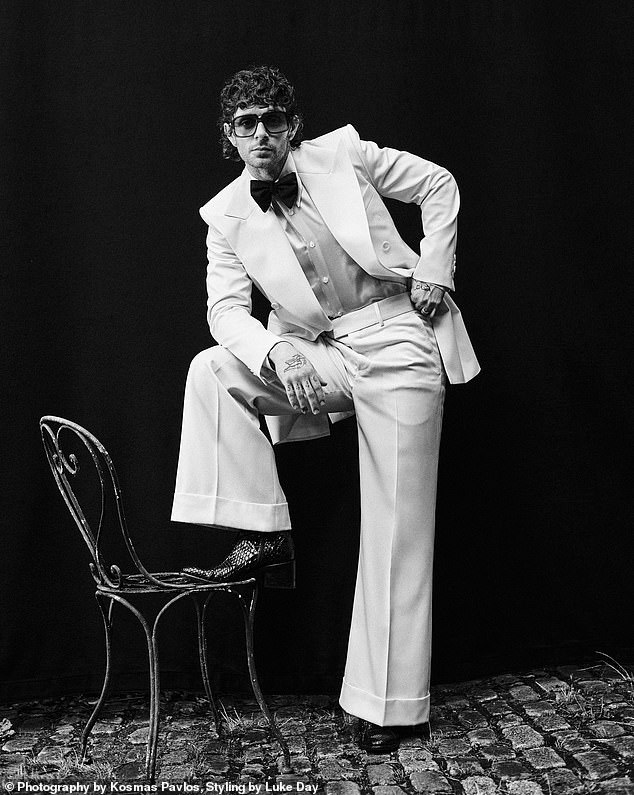 The star later showed off his suave side in a crisp white tuxedo paired with oversized sunglasses and black textured boots as he struck a pose on a balcony chair