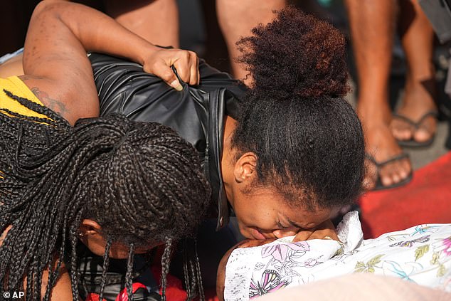 Relatives mourn beside the bodies of people killed in a gang raid on Tuesday in Brazil