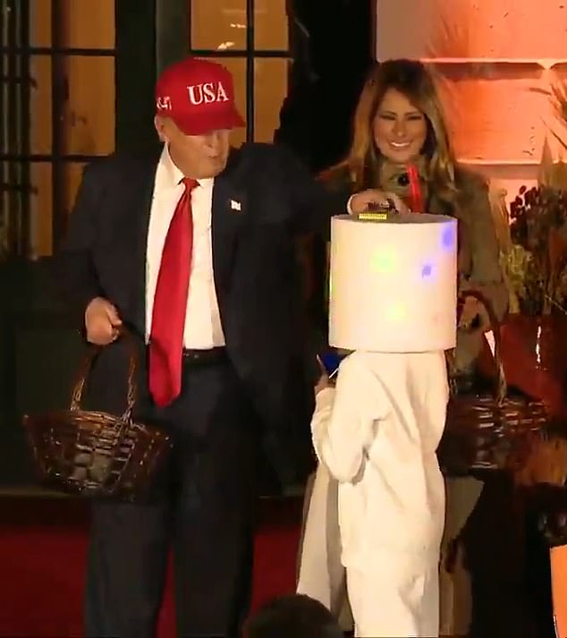 Trump revived one of his favorite trick-or-treat games from his 2019 Halloween party by bopping a child on the head with a chocolate bar, before placing it atop his costume for the child to collect