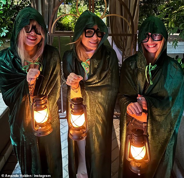 Elsewhere Amanda Holden (centre) channelled famous friend Alan Carr from Celebrity Traitors in her second Halloween costume of the year  (pictured with her daughters)