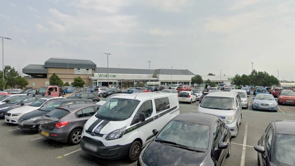 The exterior of a Waitrose supermarket from a busy parking lot.