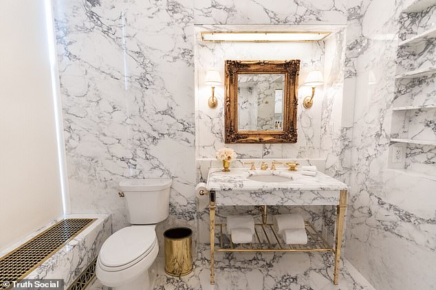 The new bathroom features a a sink set into a console table with golden legs, with an mirror set into an ornate picture frame surrounded by warm lighting