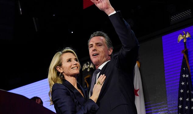Gavin Newsom and his wife Jennifer Siebel Newsom wave to supporters during a gubernatorial election night event on November 6, 2018 in Los Angeles