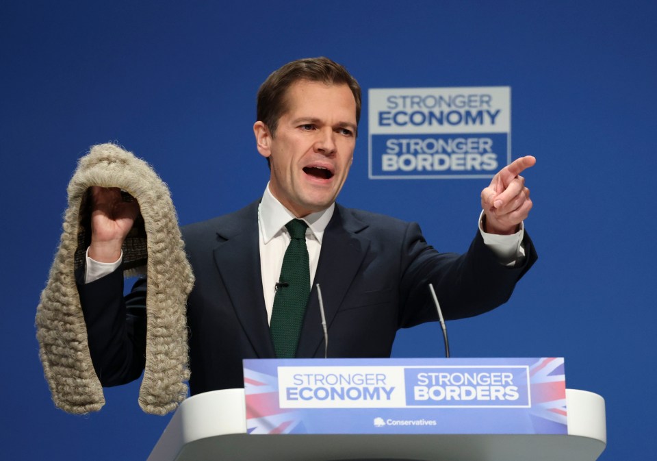 Shadow Secretary of State for Justice, Robert Jenrick, speaks on day three of the Conservative Party conference, holding a wig in one hand and pointing with the other.
