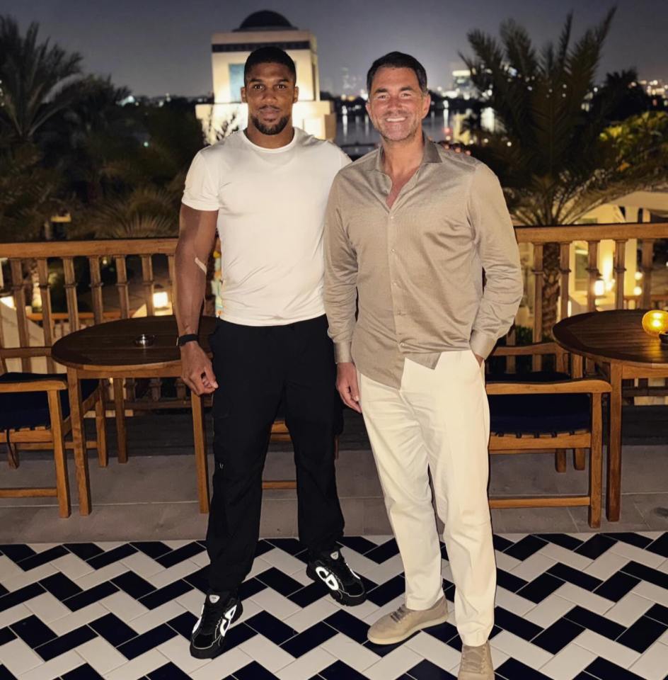 Anthony Joshua and Eddie Hearn standing side-by-side on a balcony at night.