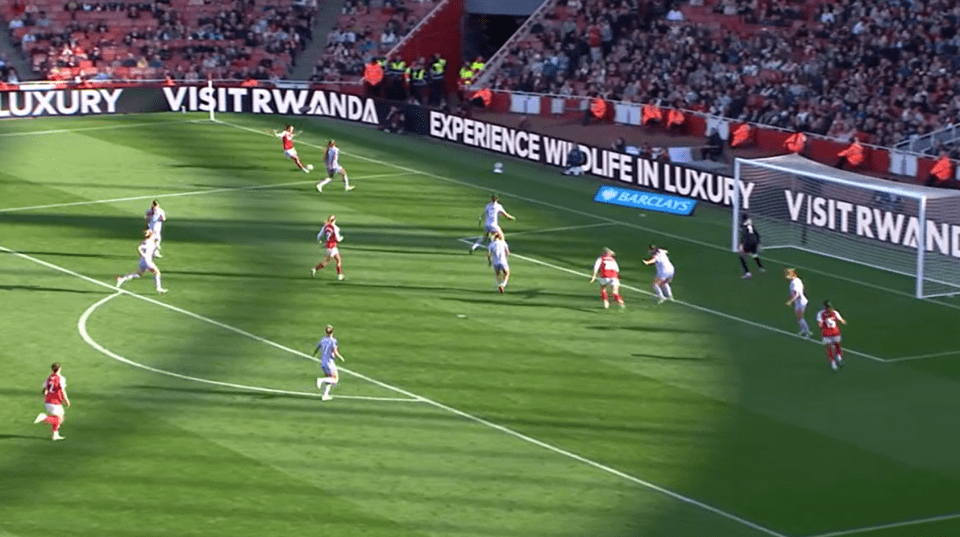 A women's soccer game in progress, with players in red and white uniforms.